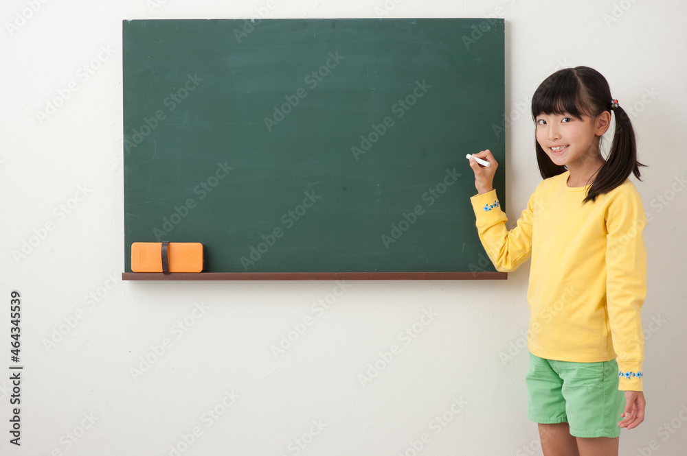 黒板の前でチョークを持つ女の子