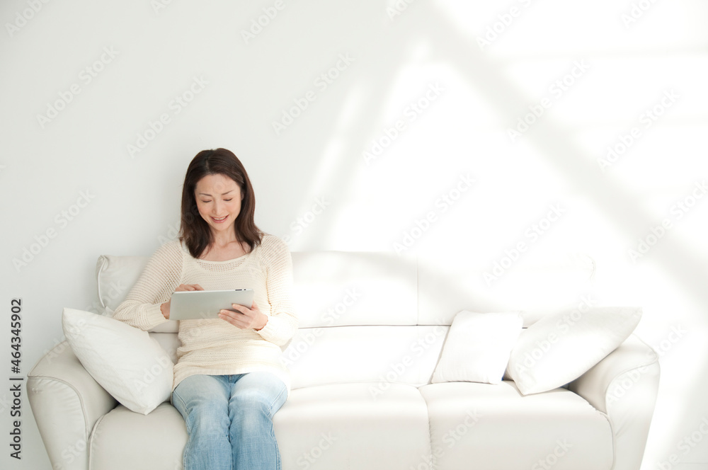 ソファに座ってタブレットＰＣを見る女性