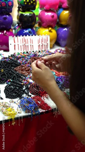 young hispanic woman looking for a gift bracelet for christmas in a fair