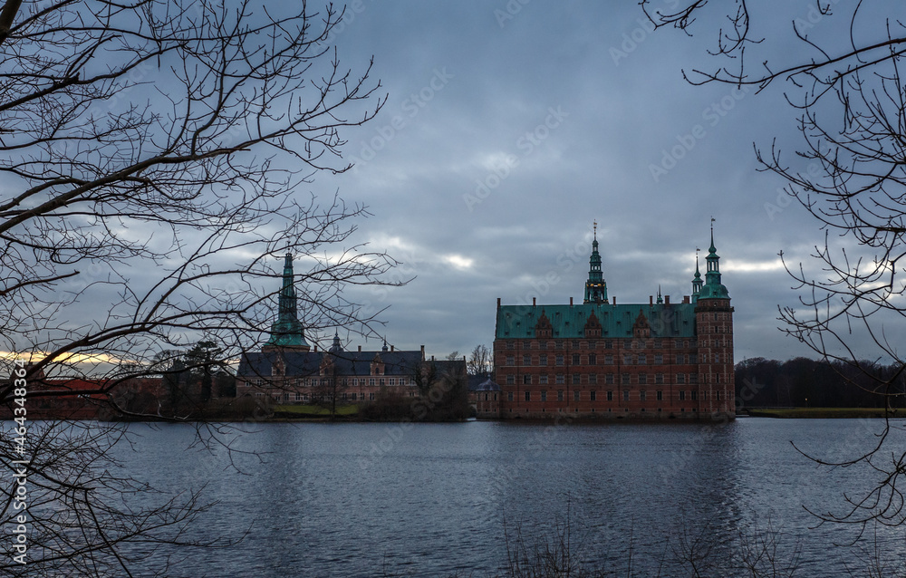 Naklejka premium Frederiksborg castle in the evening, with lake and tree in the foreground, Hillerod, Denmark