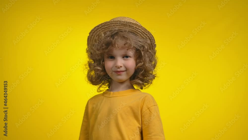 Curly girl in a straw hat is smiling thoughtfully in a yellow background studio Curly girl in a straw hat is smiling thoughtfully in a yellow background studio