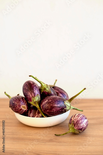 Mini eggplants in a white plate on a wooden table