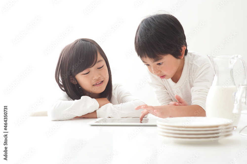 タブレットPCで遊ぶ食卓の子供男女