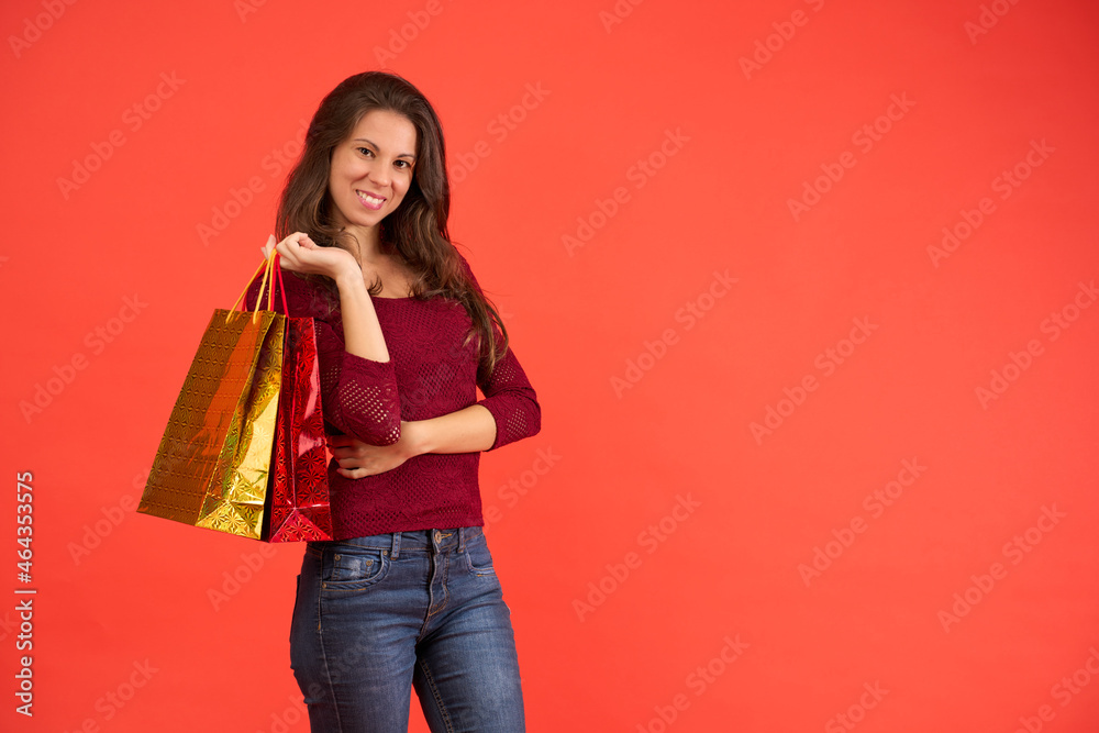 smiling brunette girl with Christmas shopping bags on an orange background smiling brunette girl with Christmas shopping bags on an orange background