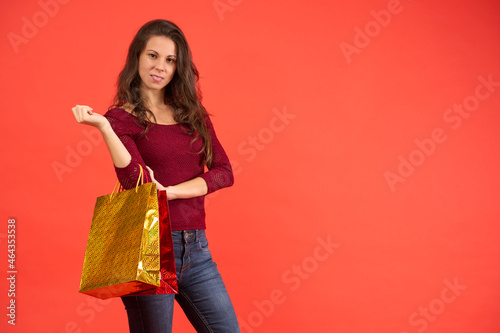 smiling brunette girl with Christmas shopping bags on an orange background