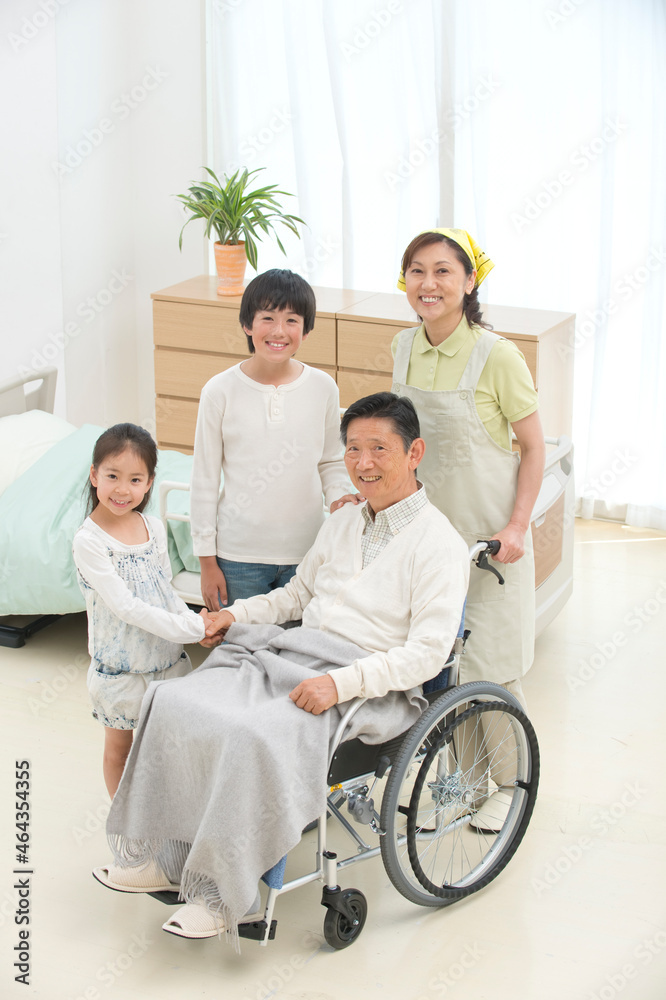 車椅子の老人と孫と介護ヘルパー