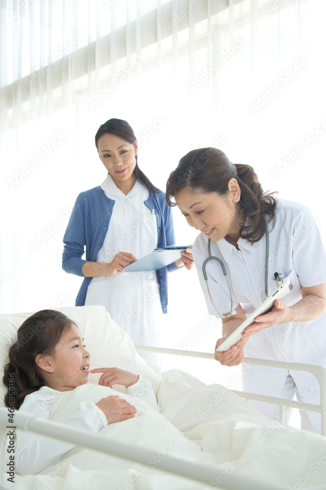 病院ベッドの女の子を診察する女医と看護師 病院ベッドの女の子を診察する女医と看護師