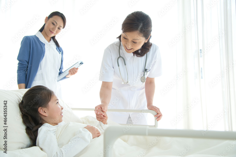 病院ベッドの女の子を診察する女医と看護師 病院ベッドの女の子を診察する女医と看護師