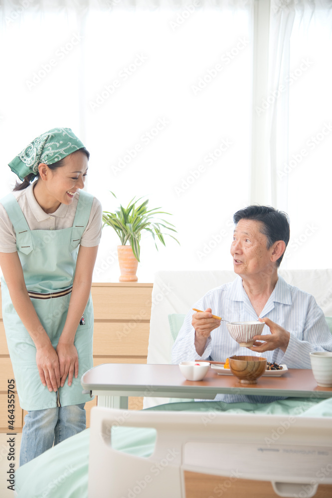 介護ベッドの老人に食事をさせる介護ヘルパー