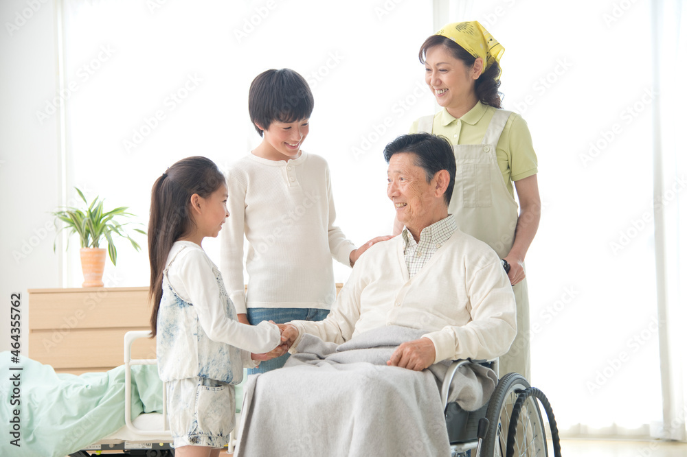 車椅子の老人と孫と介護ヘルパー