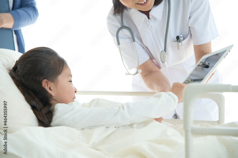 病院ベッドの女の子を診察する女医と看護師 病院ベッドの女の子を診察する女医と看護師