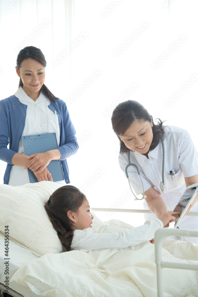 病院ベッドの女の子を診察する女医と看護師 病院ベッドの女の子を診察する女医と看護師