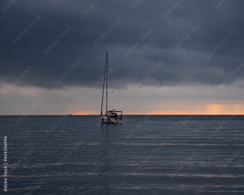 Lonely sailboat at gloomy sunset