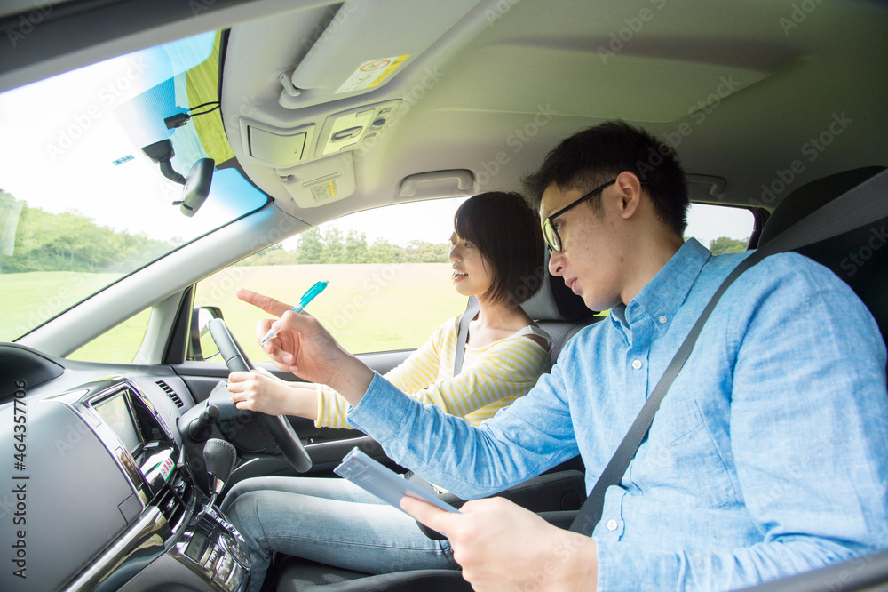 車を運転する若い女性と教習所教官 車を運転する若い女性と教習所教官