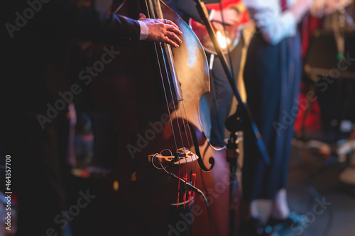 Concert view of a contrabass violoncello player with vocalist and musical band during jazz orchestra band performing music, violoncellist cello jazz player on the stage photo