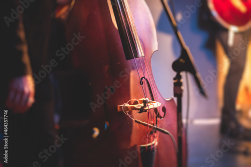 Concert view of a contrabass violoncello player with vocalist and musical band during jazz orchestra band performing music, violoncellist cello jazz player on the stage