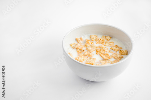Delicious breakfast. Bowl with milk on white background. Cinnamon cereal, healthy breakfast meal. Cereal squares in bowl isolated on white background.
