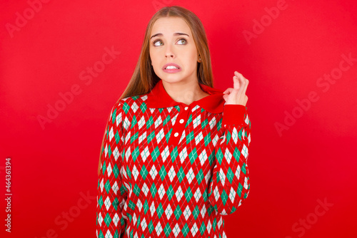 Young beautiful caucasian girl wearing christmas sweaters on red background stressed, anxious, tired and frustrated, pulling shirt neck, looking frustrated with problem © Jihan