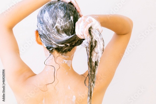 фотографія A woman standing in the shower shampooing her hair with water and shampoo