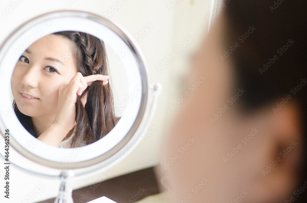鏡を見ながら髪をいじる女性 鏡を見ながら髪をいじる女性
