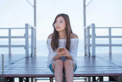 海の家に座りスマホを持つ女性