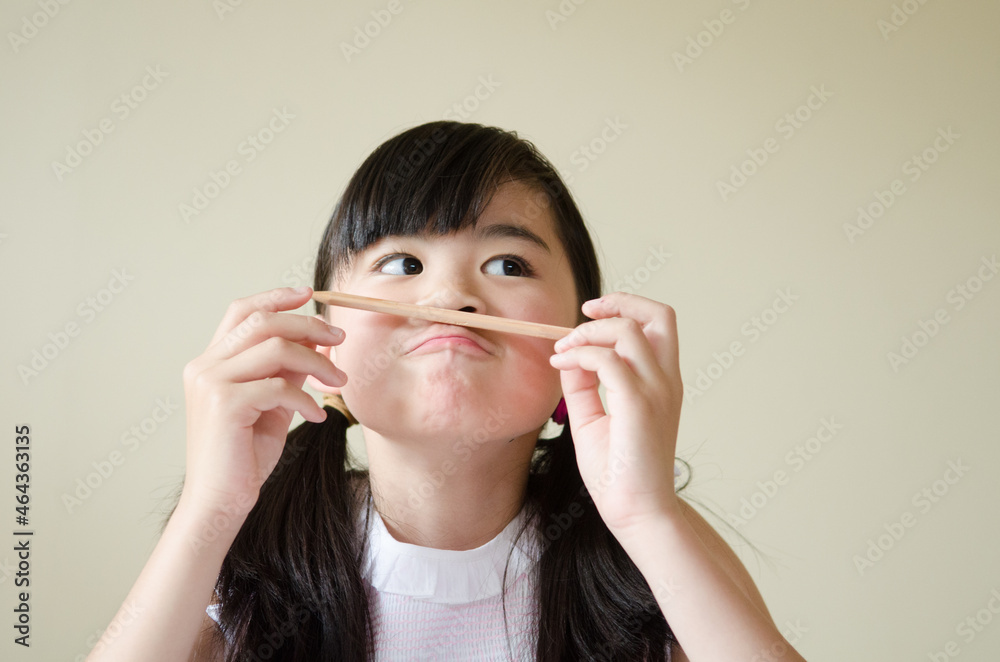 鉛筆を持っておどけた顔をする女の子 鉛筆を持っておどけた顔をする女の子