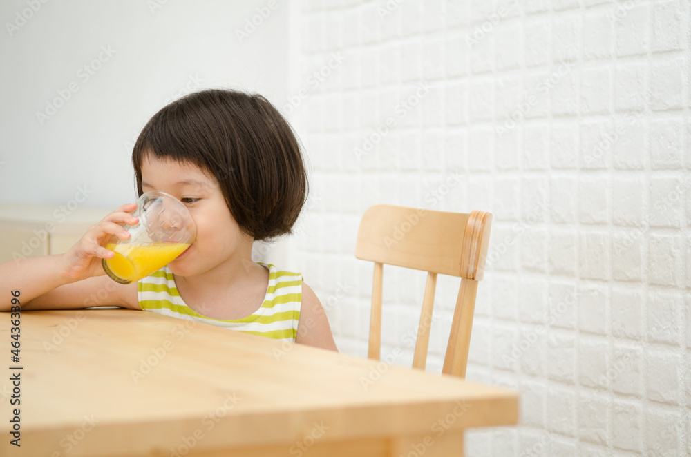 テーブルでオレンジジュースを飲んでいる女の子 テーブルでオレンジジュースを飲んでいる女の子