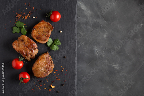 Grilled meat pieces with fresh vegetables. Barbecue steak slices on a dark background with space to copy. photo