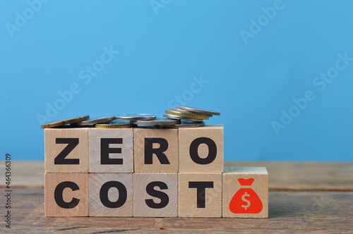 Coins, money symbol and wooden blocks with text ZERO COST photo