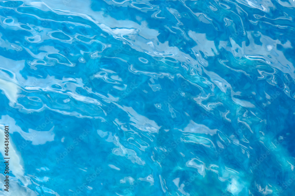 Blue water surface. Water waves with sunlight highlights . Transparent blue clear water surface texture with ripples and splashes.