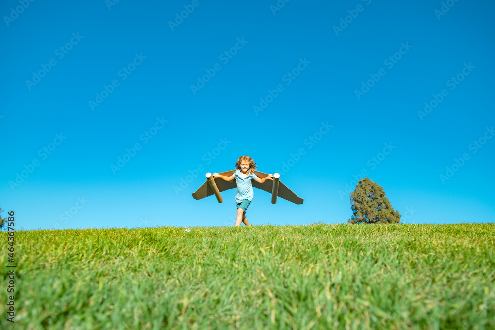 Kid pilot with toy jetpack against green grass and sky background. Happy child playing outdoors. Happy childhood. Kid pilot with toy jetpack against green grass and sky background. Happy child playing outdoors. Happy childhood.