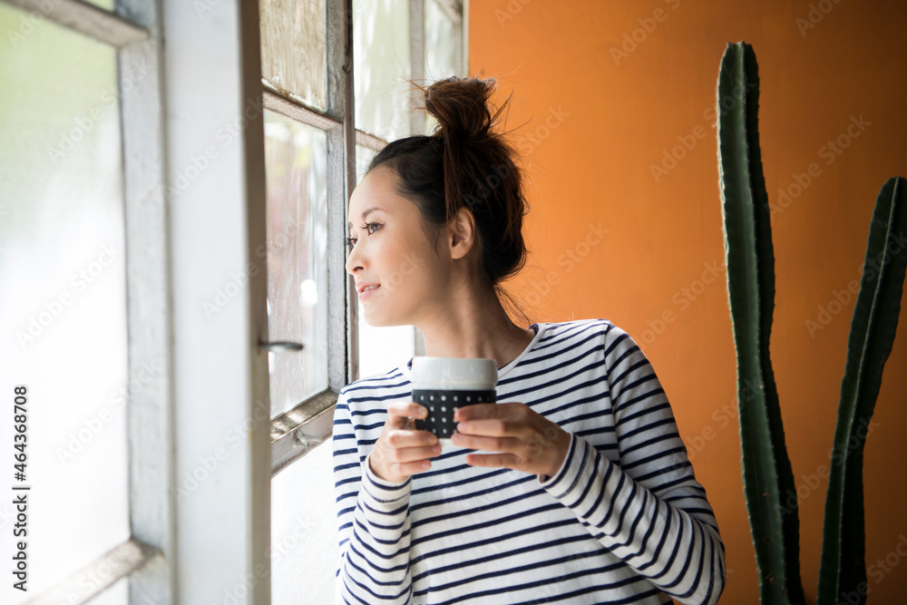 お茶を持って外を見ている女性 お茶を持って外を見ている女性