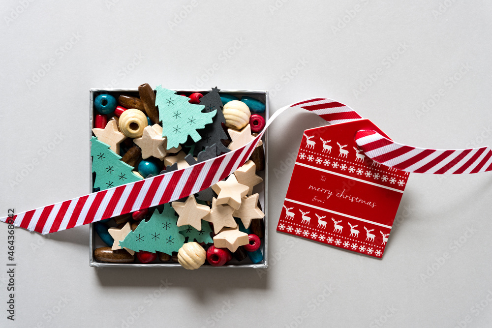 retro christmas gift tag with red and white ribbon arranged with a box of christmas objects