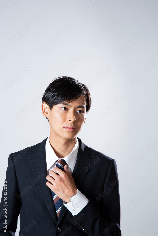ネクタイに手を添えるスーツ姿の20代男性 ネクタイに手を添えるスーツ姿の20代男性