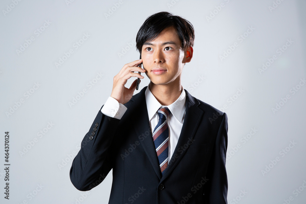 電話をするスーツ姿の20代男性 電話をするスーツ姿の20代男性
