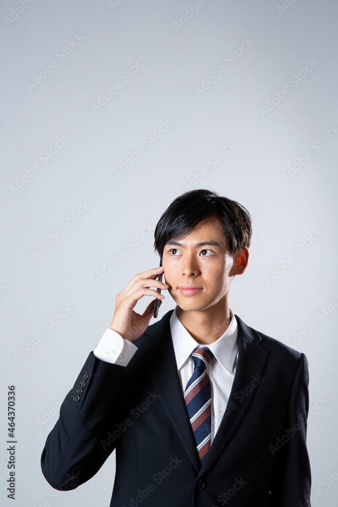 電話をするスーツ姿の20代男性 電話をするスーツ姿の20代男性
