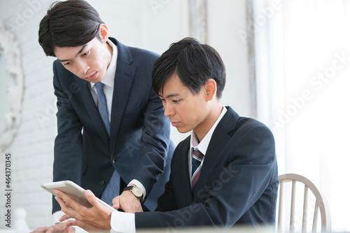 タブレットを使い説明を受けるスーツ姿の男性