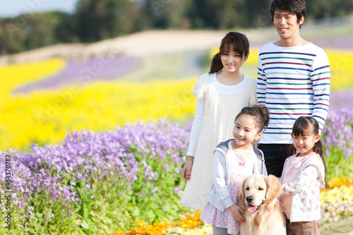 花畑で笑顔の4人家族と犬