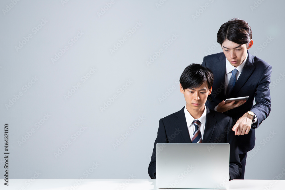 タブレットを見せ説明をするスーツ姿の男性2人