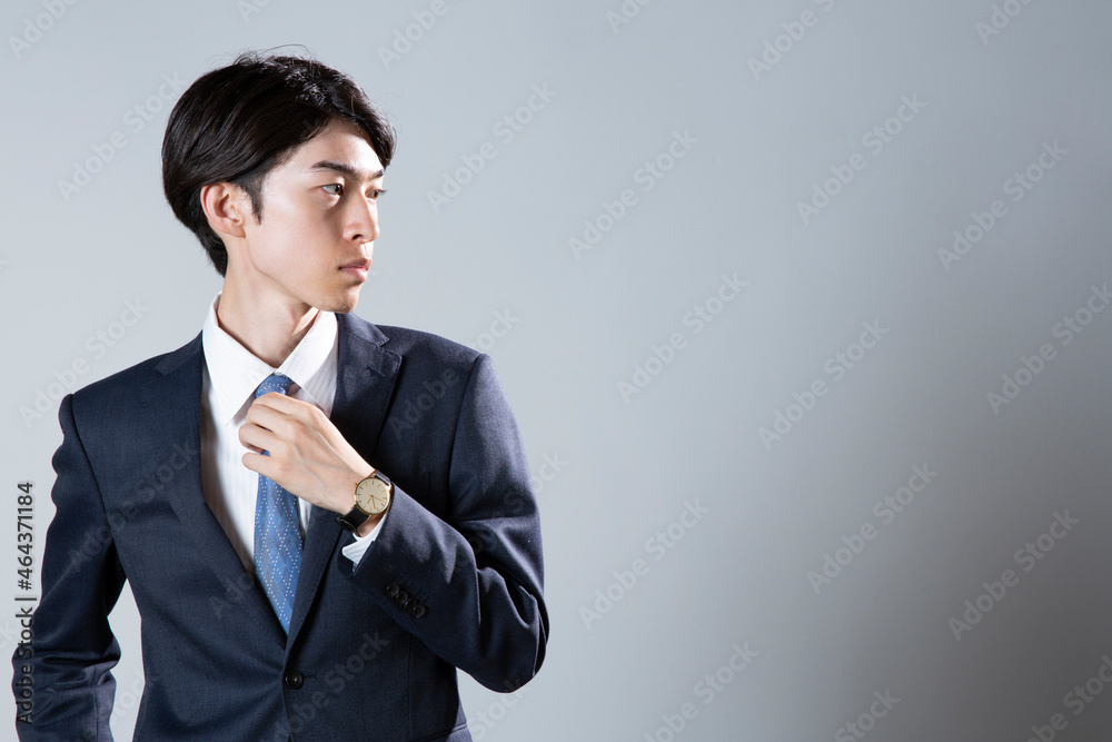 ネクタイに手を添えるスーツ姿の20代男性