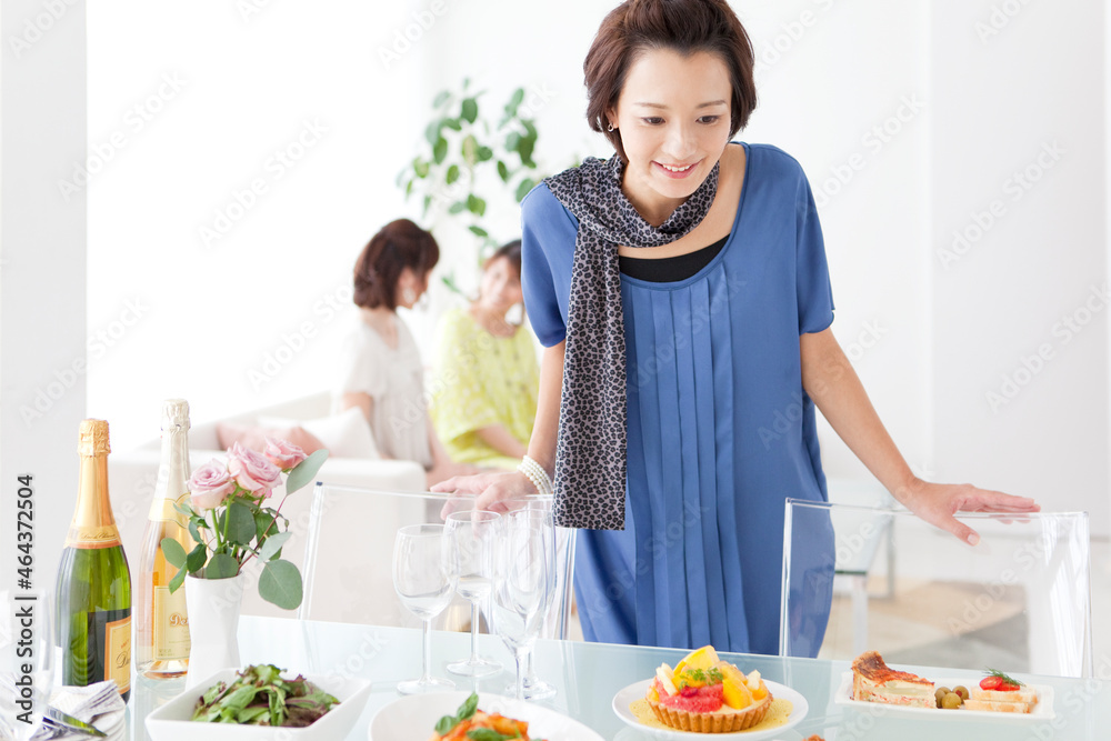 食卓に並ぶ料理を見ている笑顔の女性 食卓に並ぶ料理を見ている笑顔の女性