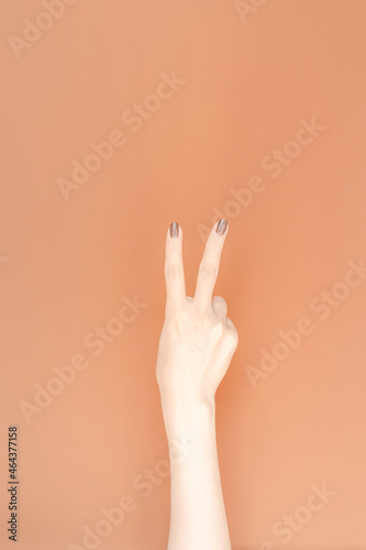 hand showing number two In front of the brown background,