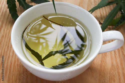 Top view hemp tea in a white cup with cannabis leaf