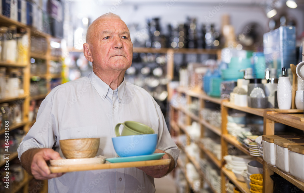 Senior man customer holding purchases and walking in a household goods store