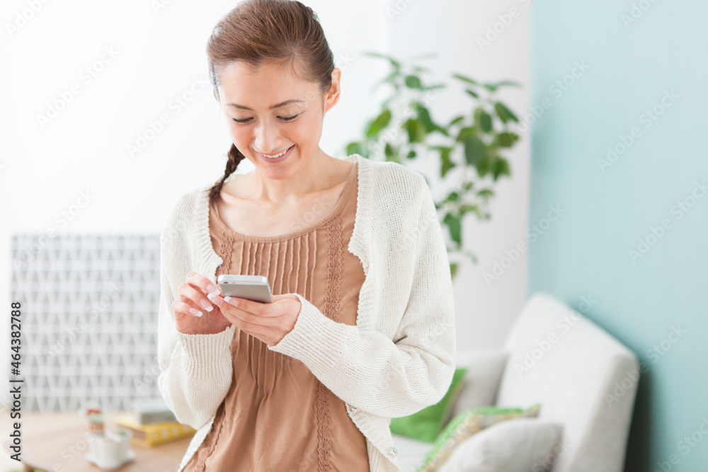 スマートフォンを操作する笑顔の女性 スマートフォンを操作する笑顔の女性
