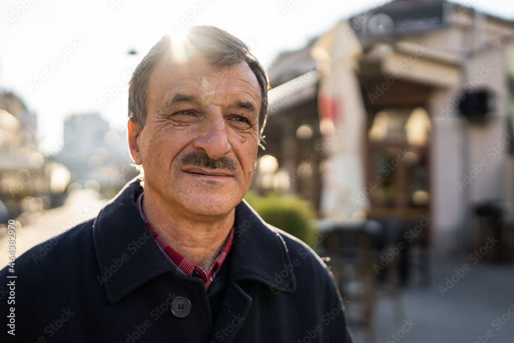 Front view portrait of senior caucasian man with mustaches standing in the city in winter or autumn day looking to the side wearing coat close up copy space Front view portrait of senior caucasian man with mustaches standing in the city in winter or autumn day looking to the side wearing coat close up copy space