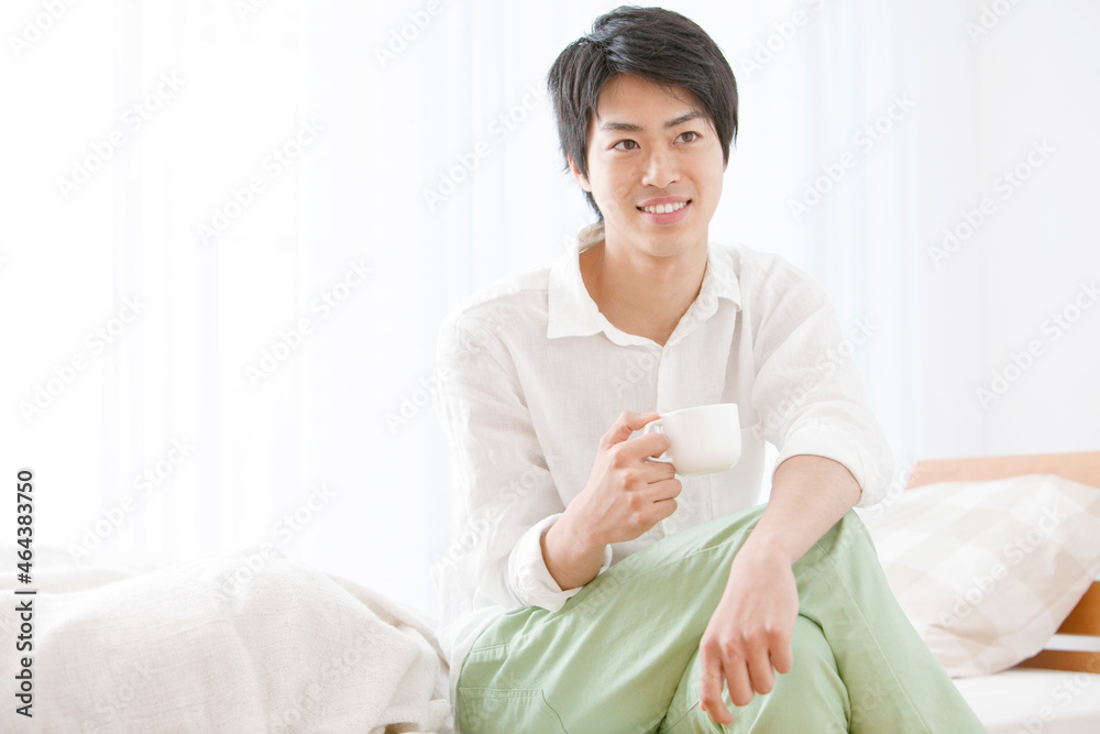 寝室でカップを持つ男性 寝室でカップを持つ男性