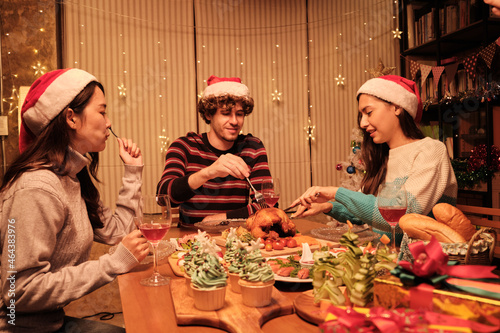 Friends enjoy fun eating diner at table with specials foods  young woman cutting roasted turkey at home s dining room  decorated with ornaments  Christmas festival  and New Year celebration party.