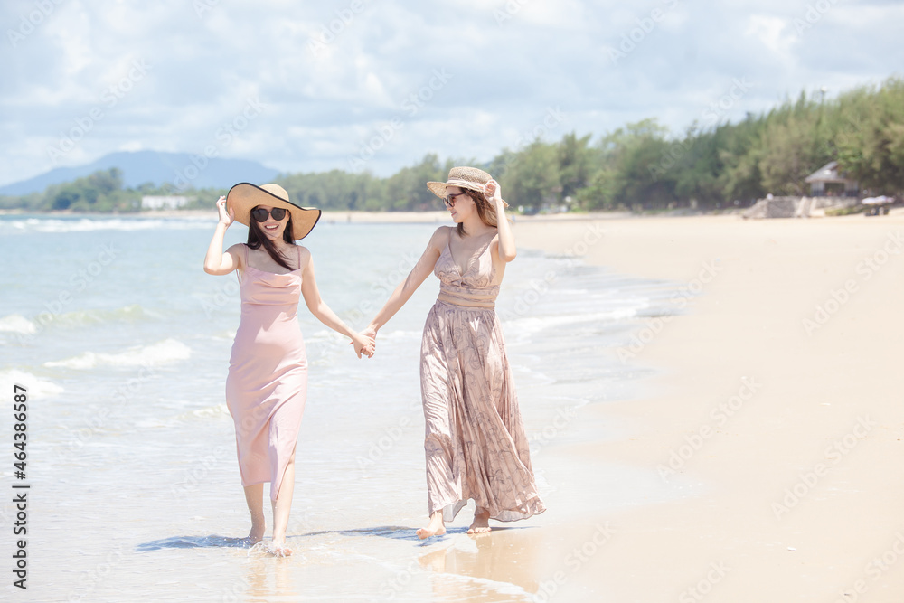 young women Asian and friends enjoying on the beach on a sunny day. Two young women Asian walking together on a beach. young women happy friends at sunset beach party runs to water young women Asian and friends enjoying on the beach on a sunny day. Two young women Asian walking together on a beach. young women happy friends at sunset beach party runs to water