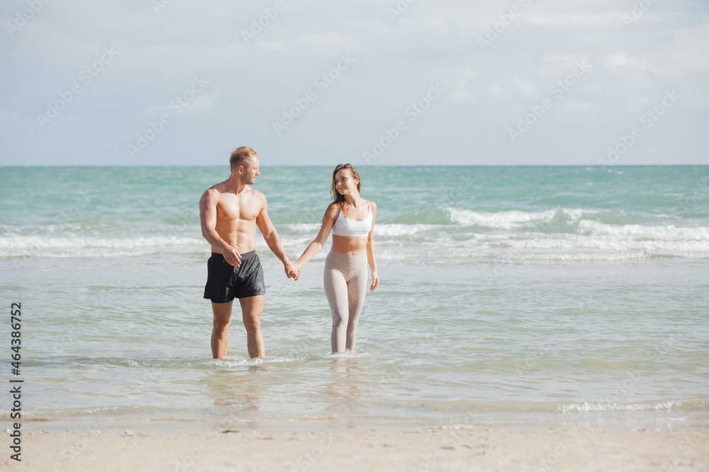 young couple walking at each other at beach. Romantic couple walking on sea, enjoying life and each other at honeymoon vacation.